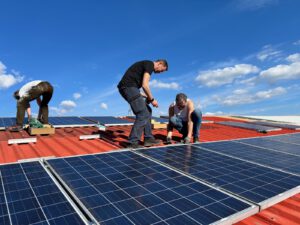 Drie mensen leggen zonnepanelen aan op een dak